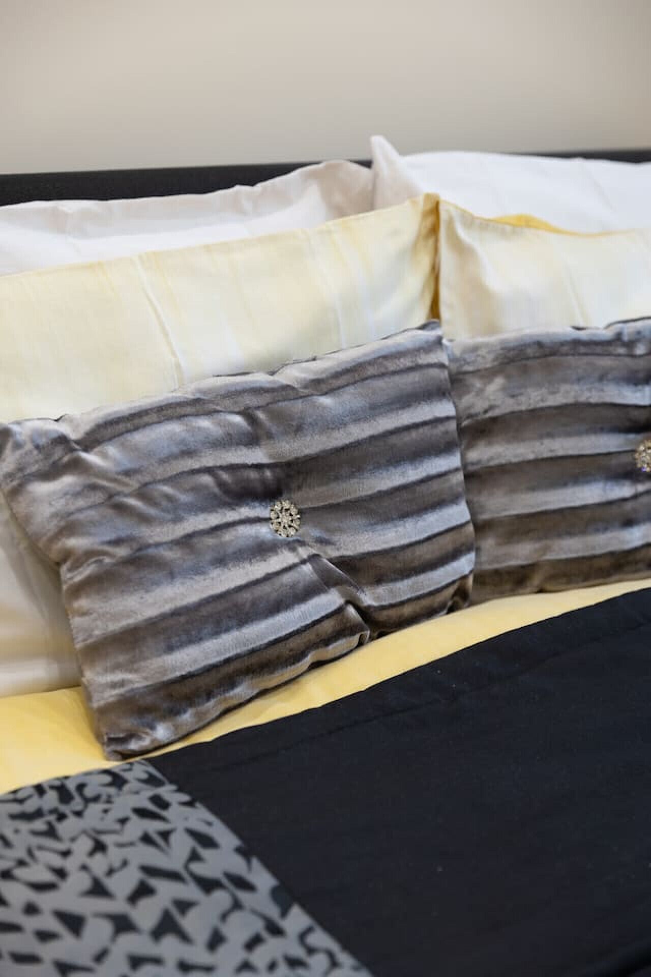 A bed with striped pillows and a patterned throw.