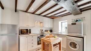 Una cocina moderna con electrodomésticos de acero inoxidable, armarios blancos y vigas de madera a la vista.