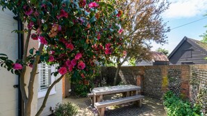A garden with a wooden bench, a brick wall, and flowering plants. - 4 Bed in Southwold (oc-hilsi) (Southwold)