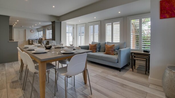 A modern kitchen with a dining area, a sofa, and a small table. - 4 Bed in Southwold (oc-hilsi) (Southwold)