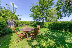 A wooden table and chairs in a garden with a hedge and trees. - 2 Bed in Field Dalling (oc-1988) (Field Dalling)