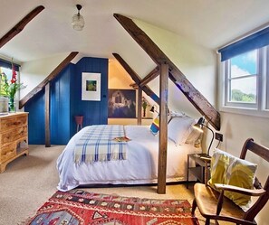 A bedroom with a sloped ceiling, a bed, a chair, a desk, and a window. - 2 Bed in Field Dalling (oc-1988) (Field Dalling)