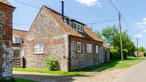 Ein Haus aus Stein mit Ziegeldach, Schornstein und einem Kiesweg.