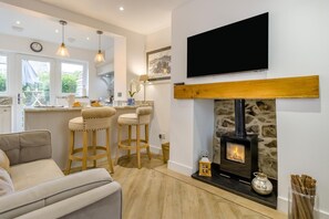 A modern kitchen with a stone fireplace, a bar area with stools, and a flat-screen TV mounted above the fireplace. - 1 Bed in Conwy (oc-bow117) (Conwy)