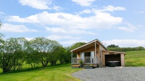 A wooden cabin with a porch, a garage, and a gravel driveway.