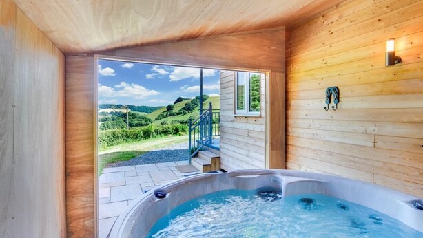 Una cabaña de madera con jacuzzi y vistas panorámicas al exterior.