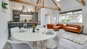 A modern kitchen with built-in appliances, a dining area with a round table and chairs, and a leather sofa in a bright room with skylights. - 1 Bed in Mitchell (oc-p00750) (Mitchell)