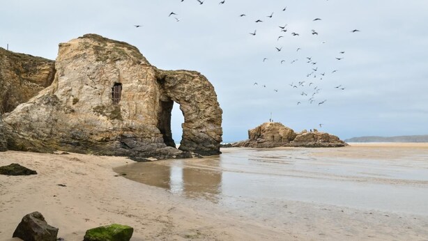 A coastal landscape with a large rock formation featuring a natural archway, a sandy beach, and a distant rocky outcrop. - 1 Bed in Mitchell (oc-p00750) (Mitchell)