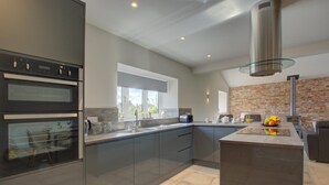 Una cocina moderna con electrodomésticos integrados, una isla grande y una pared decorativa de ladrillo.
