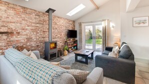 Una sala de estar con pared de ladrillo, chimenea, sofá, mesa de centro y televisor.