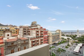 Un paysage urbain côtier avec des immeubles à étages, un beffroi imposant et un port de plaisance.