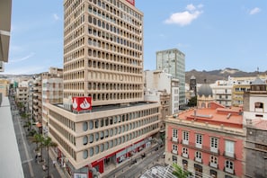 Un immeuble à plusieurs étages, orné d’une horloge bien visible sur sa façade, entouré d’autres bâtiments et avec un ciel dégagé en arrière-plan.