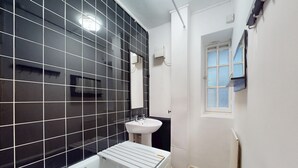 Ein Badezimmer mit einer Badewanne, einem weißen Waschbecken und schwarzen Fliesenwänden.
