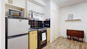 Eine kompakte Küche mit Kühlschrank, Herd, Mikrowelle und einem kleinen Spülbecken.