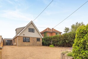 A residential property with a gravel driveway, a detached garage, and a well-maintained garden with various shrubs and plants.