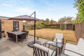 A patio area with a table and chairs, a standing umbrella, and a small round table with a glass top.