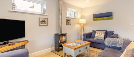 A living room with a television, sofa, and a fireplace.