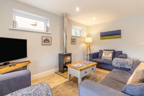 Ein Wohnzimmer mit Fernseher, einer Couch und einem Kamin.