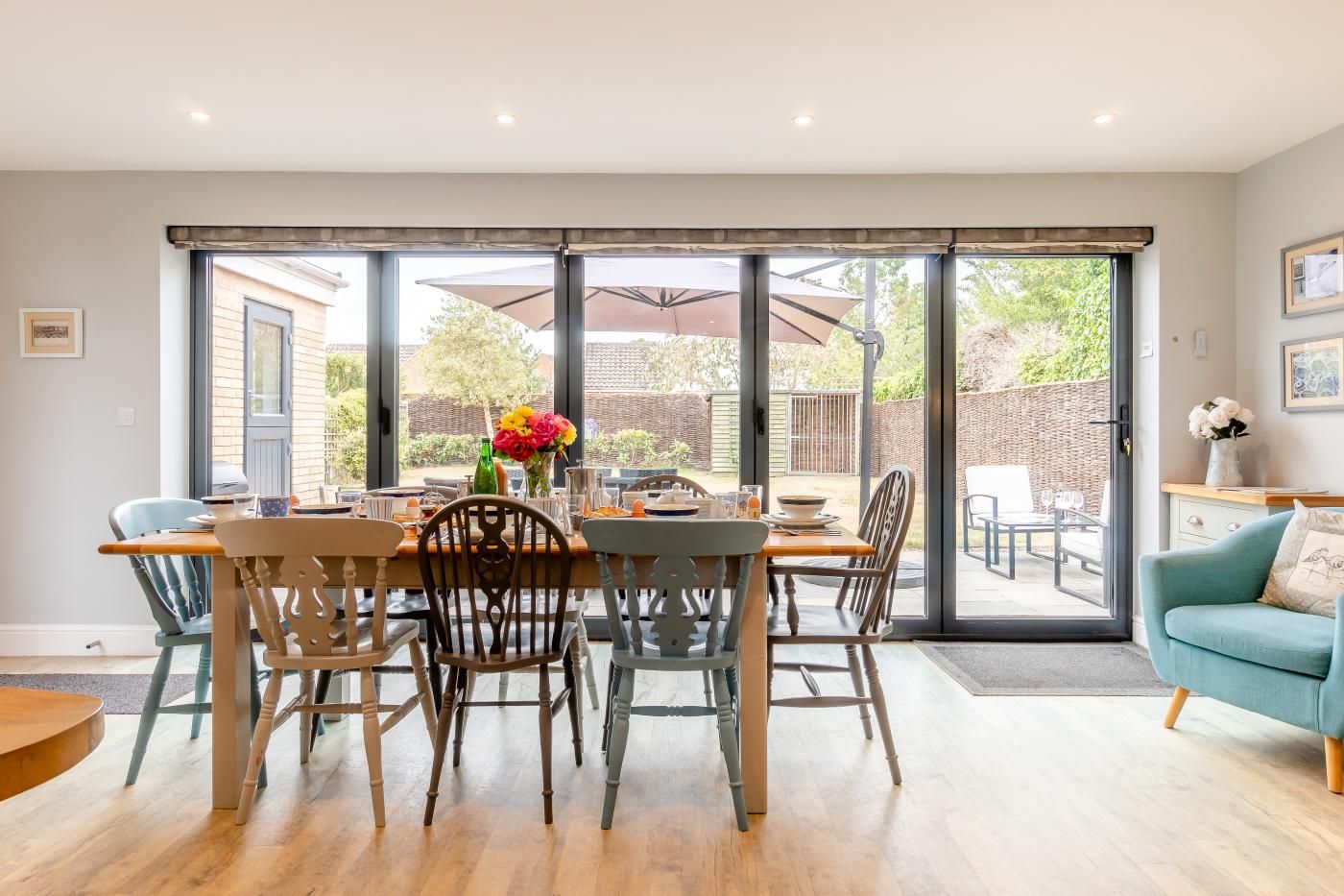Un comedor con una mesa dispuesta para cuatro personas, un sofá y un ventanal corredero que da a un patio exterior.