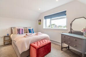 Un dormitorio con cama, mesita de noche, cómoda y ventana.