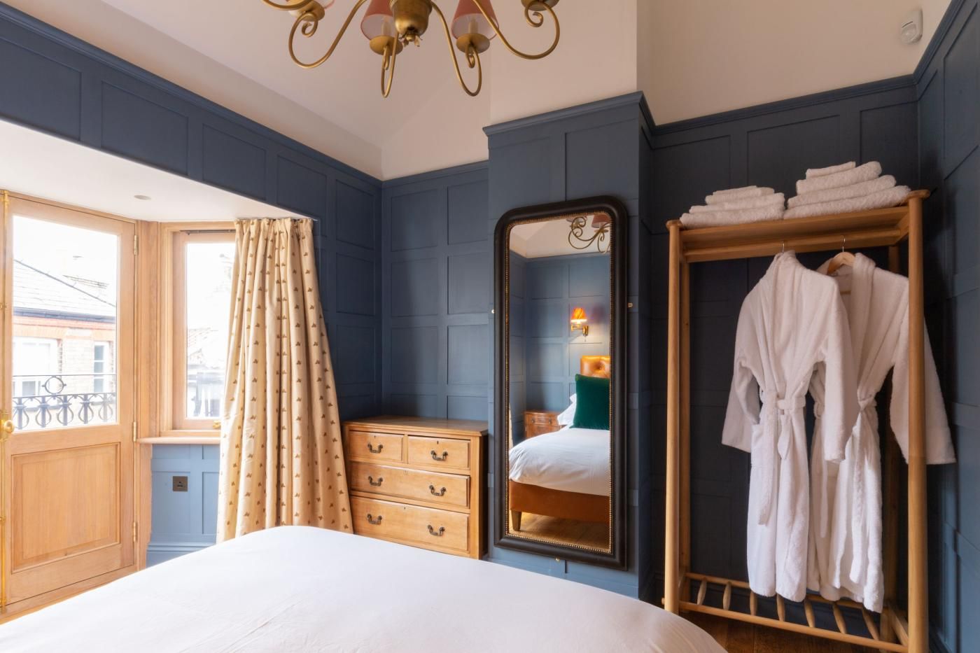 A bedroom with a bed, a dresser, a mirror, and a wardrobe with towels.