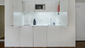 A compact kitchen with white cabinets, a microwave, a coffee maker, and a sink. - Extendall 1 in Oporto (Porto)