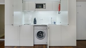 A compact kitchen with a built-in washing machine, microwave, and sink. - Extendall 1 in Oporto (Porto)
