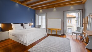 Ein Schlafzimmer mit Bett, Schreibtisch, Stuhl und Blick ins Freie.