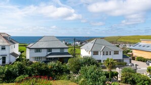 A coastal residential area with white houses, a view of the sea, and lush greenery. - 3 Bed in Trevone (oc-p00758) (Trevone)