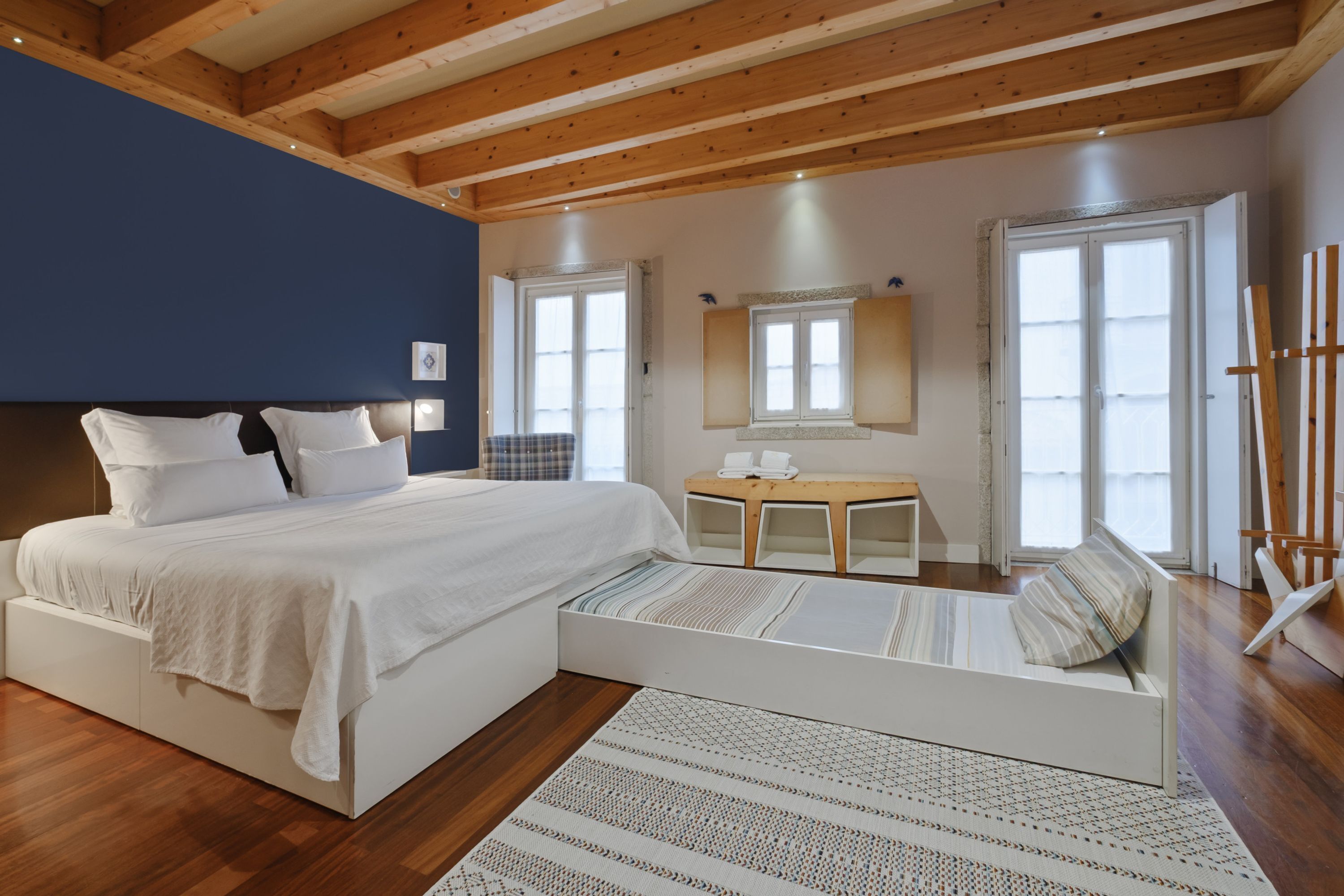 Quarto com cama, mesa de cabeceira e uma pequena mesa redonda.