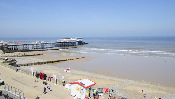 A beach with a pier, a lifeguard station, and a small kiosk.