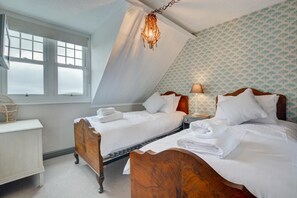 A bedroom with two wooden beds, a nightstand, a lamp, and a window with a view. - 6 Bed in Cromer (oc-1996) (Cromer)