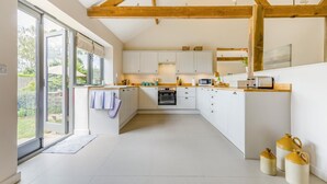 Una cocina moderna con armarios blancos, horno empotrado y un ventanal grande.