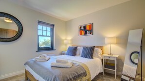 A neatly arranged bedroom with a bed, bedside tables, a window, and a mirror. - 2 Bed in Mundesley (oc-1991) (Mundesley)