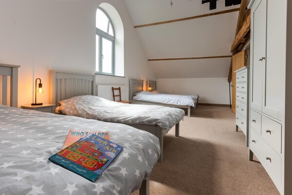 A bedroom with two beds, a window, a radiator, and a wardrobe. - 4 Bed in White Horse Common (oc-1945) (Witton)