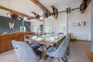 A dining area with a long table set for a meal, surrounded by cushioned seating. - 4 Bed in White Horse Common (oc-1945) (Witton)