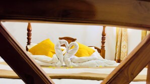 Ein Bett mit hölzernem Kopfteil, weißer Bettwäsche und zwei gelben Kissen.