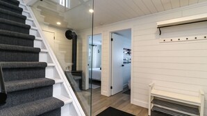 En trappe fører op til et soveværelse med en glasdør, en hvid bænk og en reol på væggen.