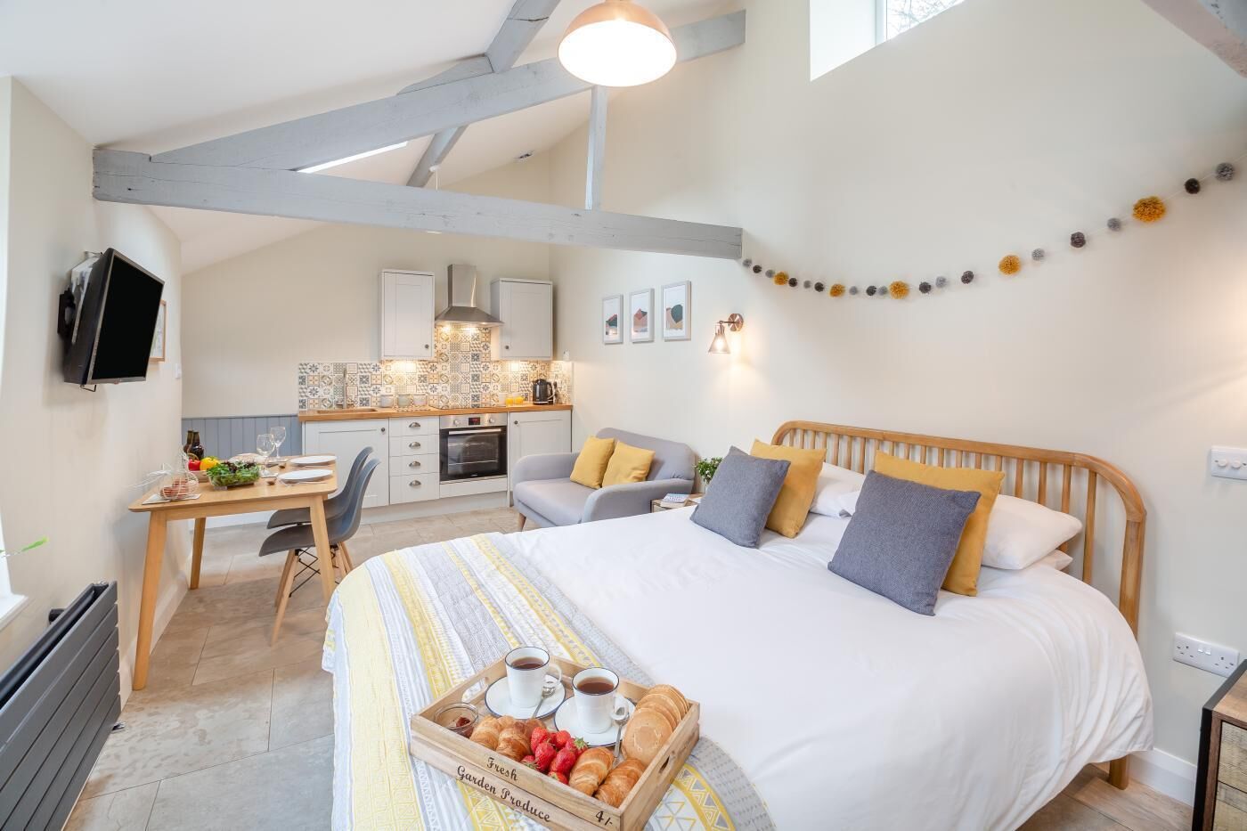 Ein gemütliches Schlafzimmer mit Bett, Nachttisch und Frühstücksbrett mit Croissants und Kaffee.