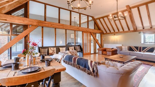Ein geräumiger Loft mit freiliegenden Holzbalken, einem großen Esstisch und einer gemütlichen Sitzecke mit Sofas und einem Couchtisch.