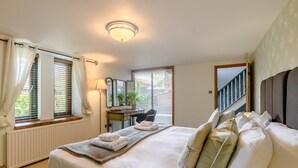 Ein Hotelzimmer mit einem großen Bett, einem Schreibtisch, einem Sessel und Blick aus den Fenstern.