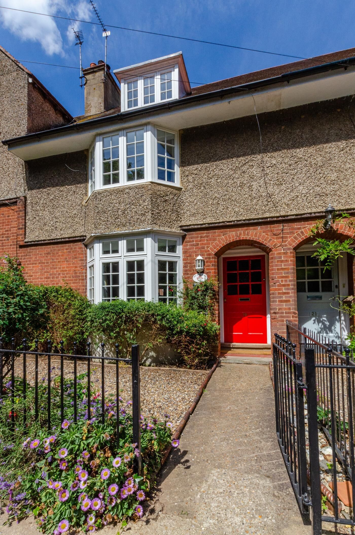 A two-story house with a red door, white windows, and a brick exterior.