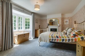 A bedroom with a bed, a dresser, a chest of drawers, a window with curtains, a fireplace, and a mirror on the wall. - 4 Bed in Mundesley (oc-1997) (Mundesley)