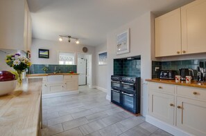 A modern kitchen with a central island, a double oven, and a coffee maker on the countertop. - 4 Bed in Mundesley (oc-1997) (Mundesley)