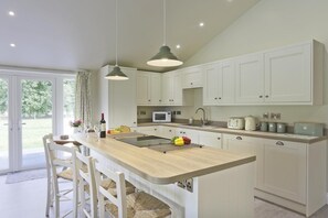 Una cocina moderna con una isla central, armarios blancos y un ventanal amplio.