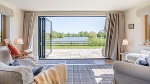 A room with a large sliding glass door leading to a terrace with a view of a lake. - 3 Bed in Bassaleg (oc-bow138) (Bassaleg)