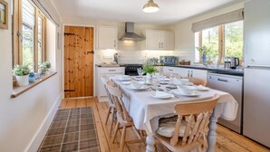 A modern kitchen with white cabinets, a dining table set for six, and a large window providing natural light. - 3 Bed in Bassaleg (oc-bow138) (Bassaleg)