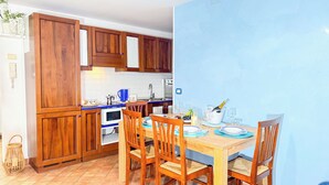 Una cocina compacta con armarios de madera, horno empotrado y una mesa de comedor preparada para seis personas.