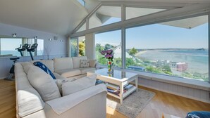 Un salon spacieux doté d’une grande fenêtre donnant sur la mer et une plage.