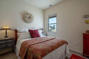 A bedroom with a bed, a nightstand, a lamp, a window, and a decorative wall piece. - Casa Bella - Hot tub, well equipped and mountain views (Santa Fe)